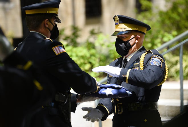 Two officers fold the flag that covered the casket of Officer Charles Edward Roberts III, outside of the Glen Ridge Municipal Complex during a memorial service in Glen Ridge on 05/14/20.