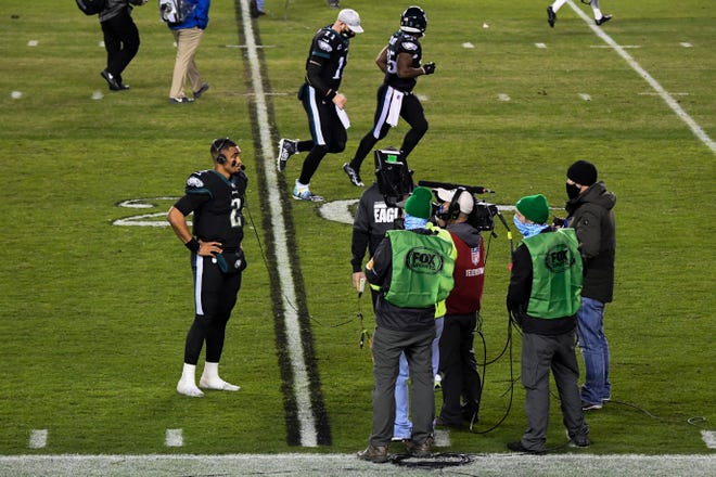 Eagles' Carson Wentz (11) jogs off the field as his replacement Jalen Hurts (2) is interviewed after a 24-21 win over the Saints in his first career start Sunday, Dec. 13, 2020 in Philadelphia.