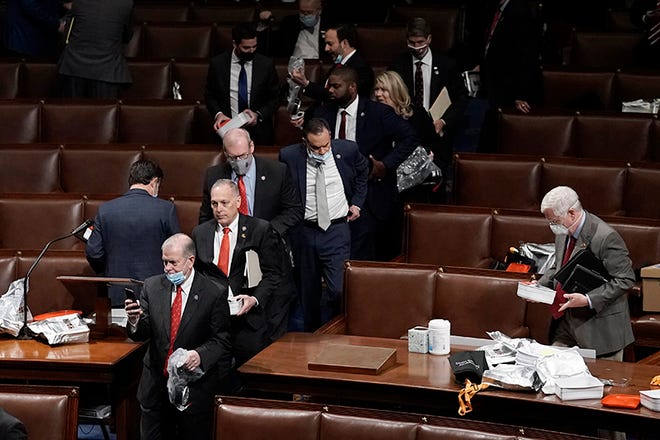 House of Representatives members leave the floor of the House chamber as protesters try to break into the chamber at the U.S. Capitol on Wednesday, Jan. 6, 2021, in Washington. (AP Photo/J. Scott Applewhite) ORG XMIT: DCSA318