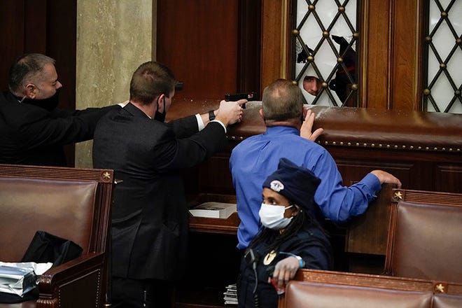 Police with guns drawn watch as protesters try to break into the House Chamber at the U.S. Capitol on Wednesday, Jan. 6, 2021, in Washington. (AP Photo/J. Scott Applewhite) ORG XMIT: DCSA316