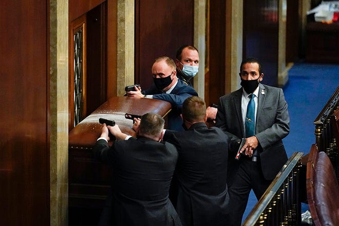U.S. Capitol Police with guns drawn stand near a barricaded door as rioters try to break into the House Chamber at the U.S. Capitol on Wednesday.